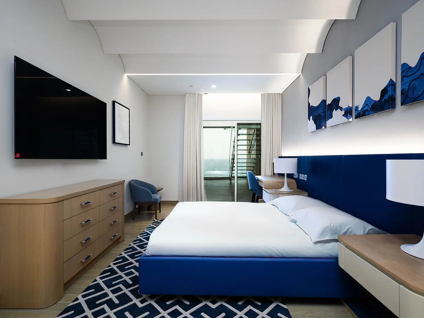Modern blue bedroom with TV and ocean view