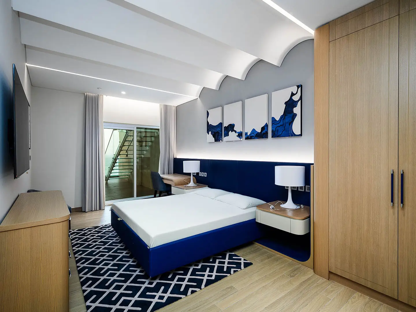 A bedroom with a blue bed, a desk, and a wardrobe